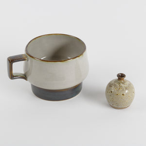 Tiny pottery vase shown next to teacup